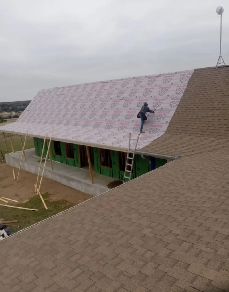 Worker preparing underlayment for a metal roof installation in La Mesa